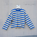 Blue and yellow striped shirt on a hanger against a gray concrete wall.