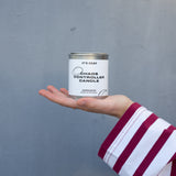 Hand holding a 'Chaos Controller Candle' can against a gray background