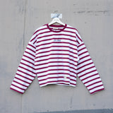 Red and white striped shirt on a hanger against a gray concrete wall.