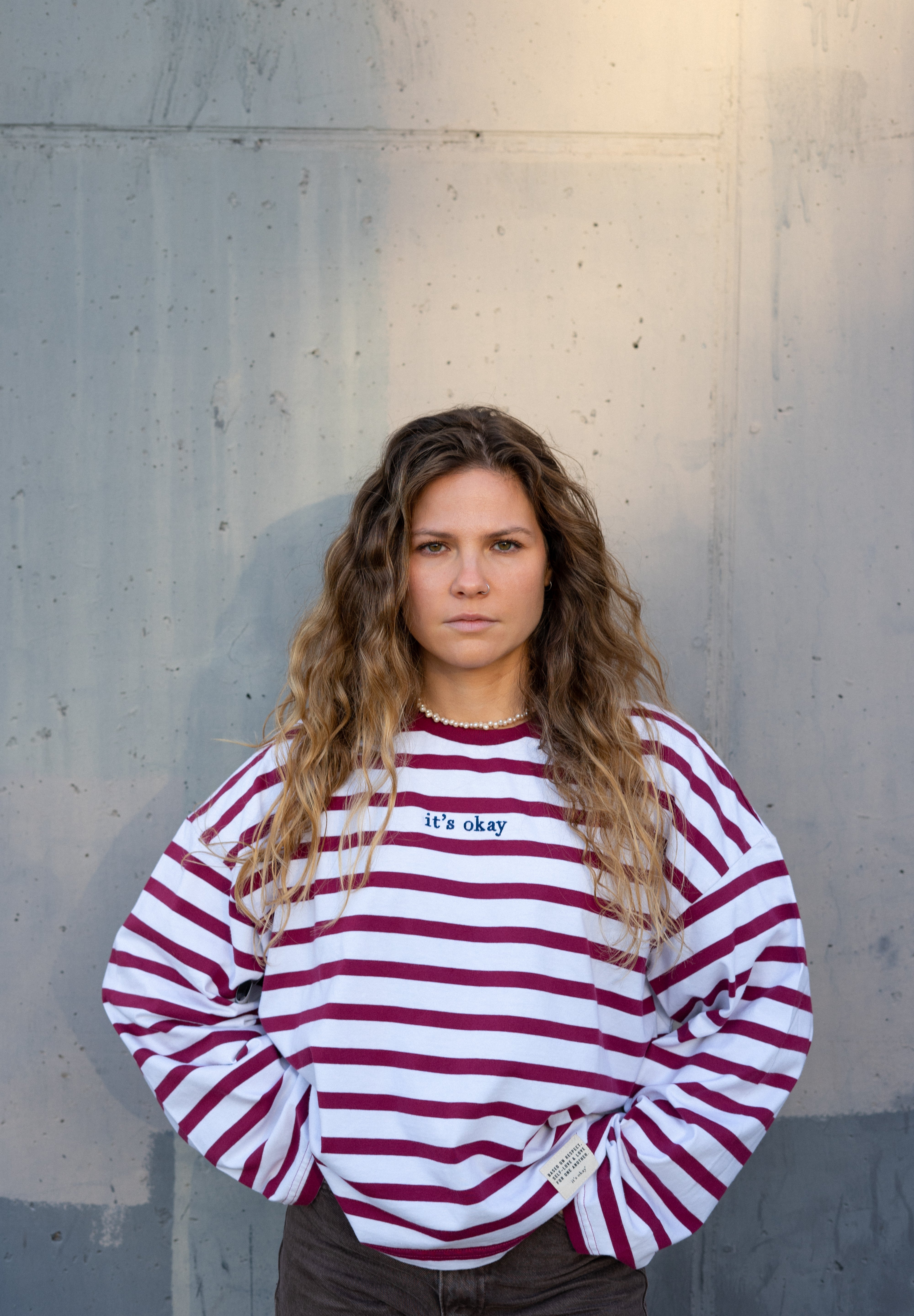 Woman wearing a red and white striped sweater against a concrete wall