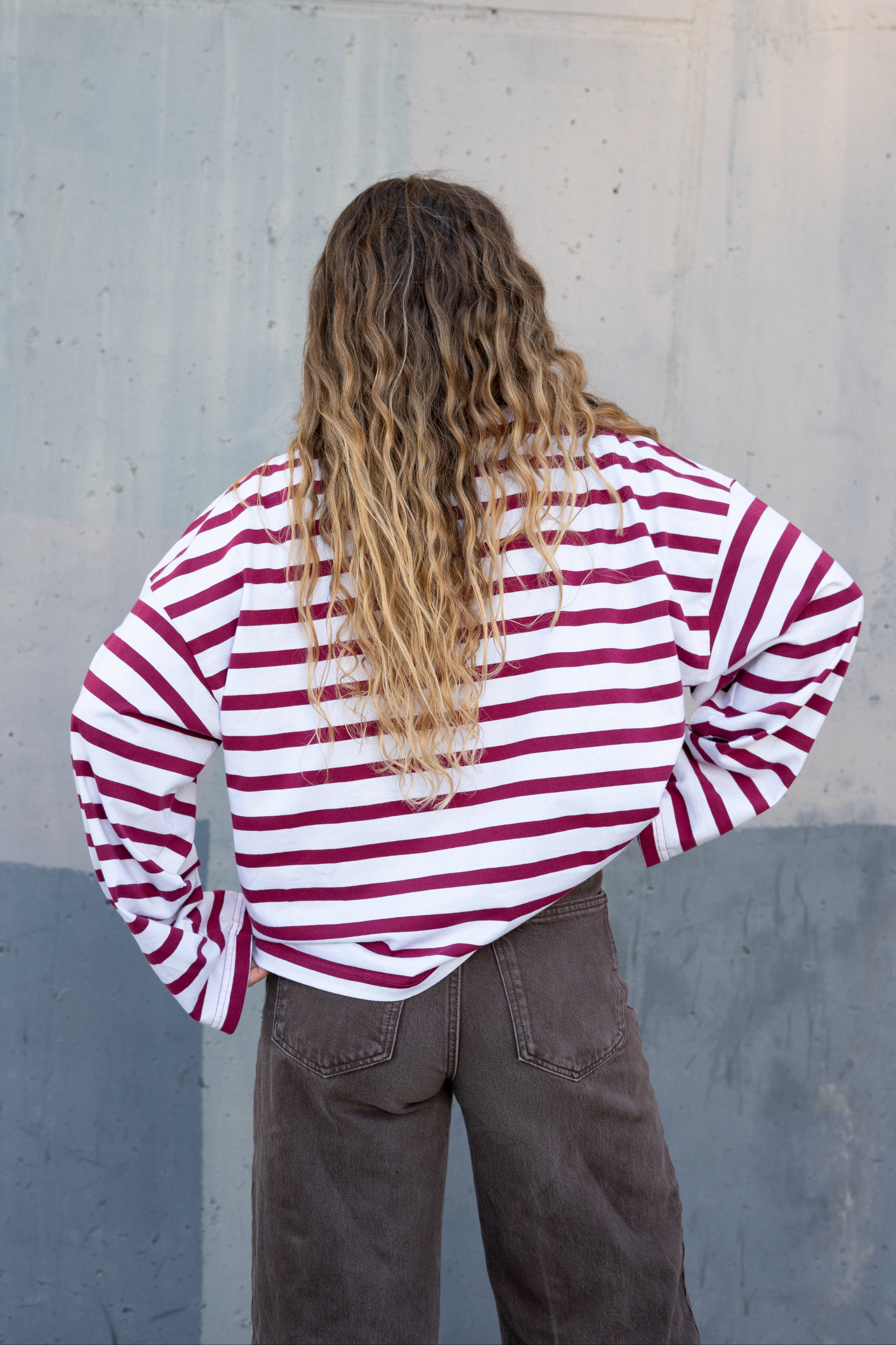Person wearing a red and white striped shirt against a gray wall