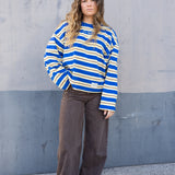 Woman wearing a blue and yellow striped sweater against a gray wall.