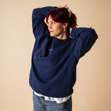 Woman wearing blue IT’S OKAY organic cotton crewneck, relaxed oversized fit with arms raised.