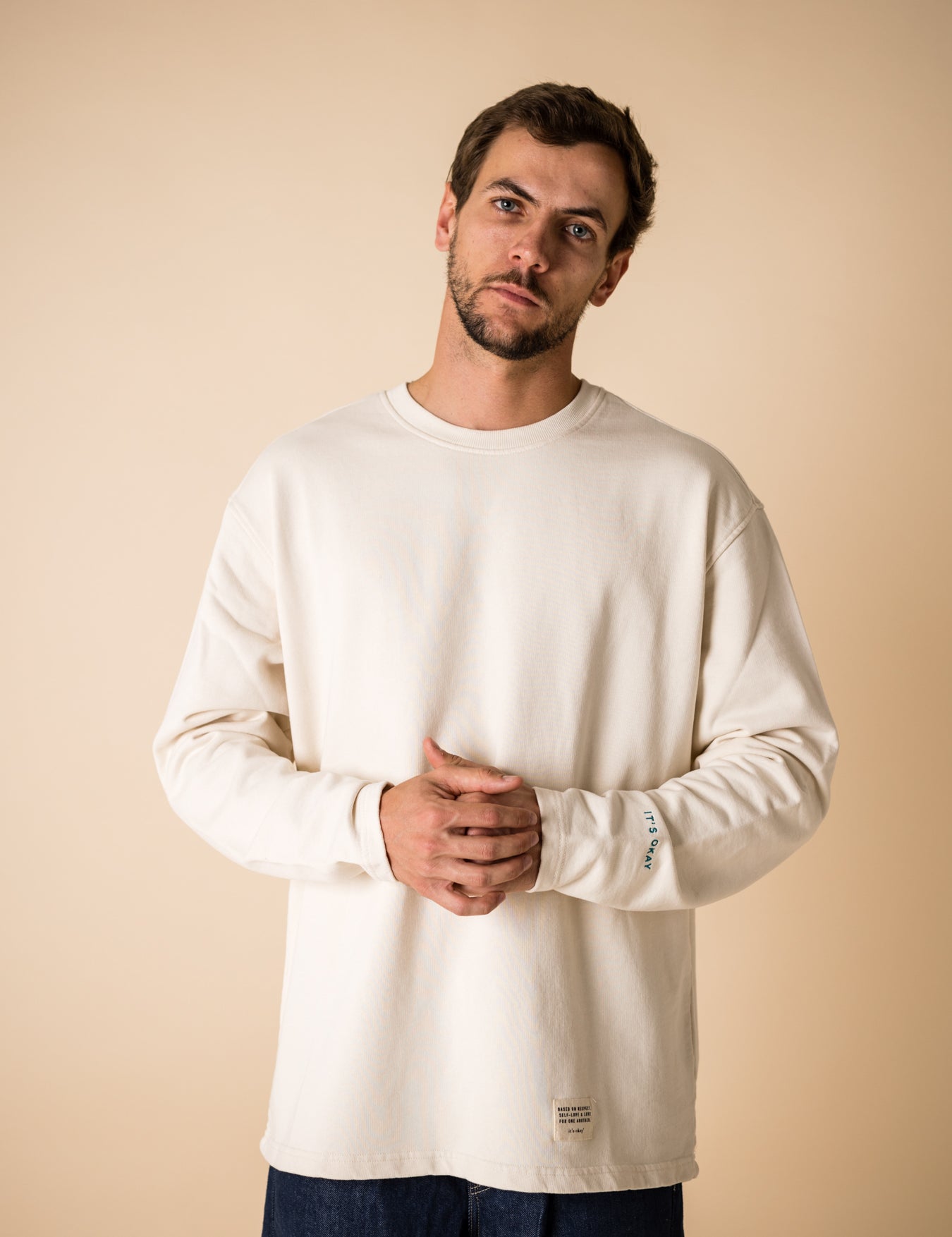 Blond man wearing an organic crew neck sweater in off-white, seamless design. Relaxed and minimal style, perfect for any occasion. Studio Photography gender neutral apparel