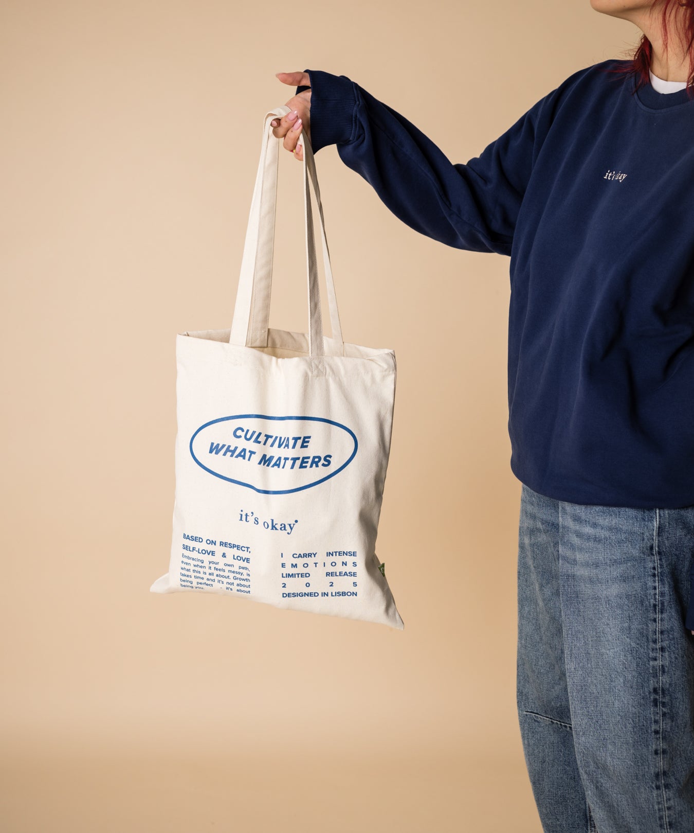 organic tote bag cultivate what matters, screenprinting, white and blue. Girl witrh crew blue pick up the tote bag.