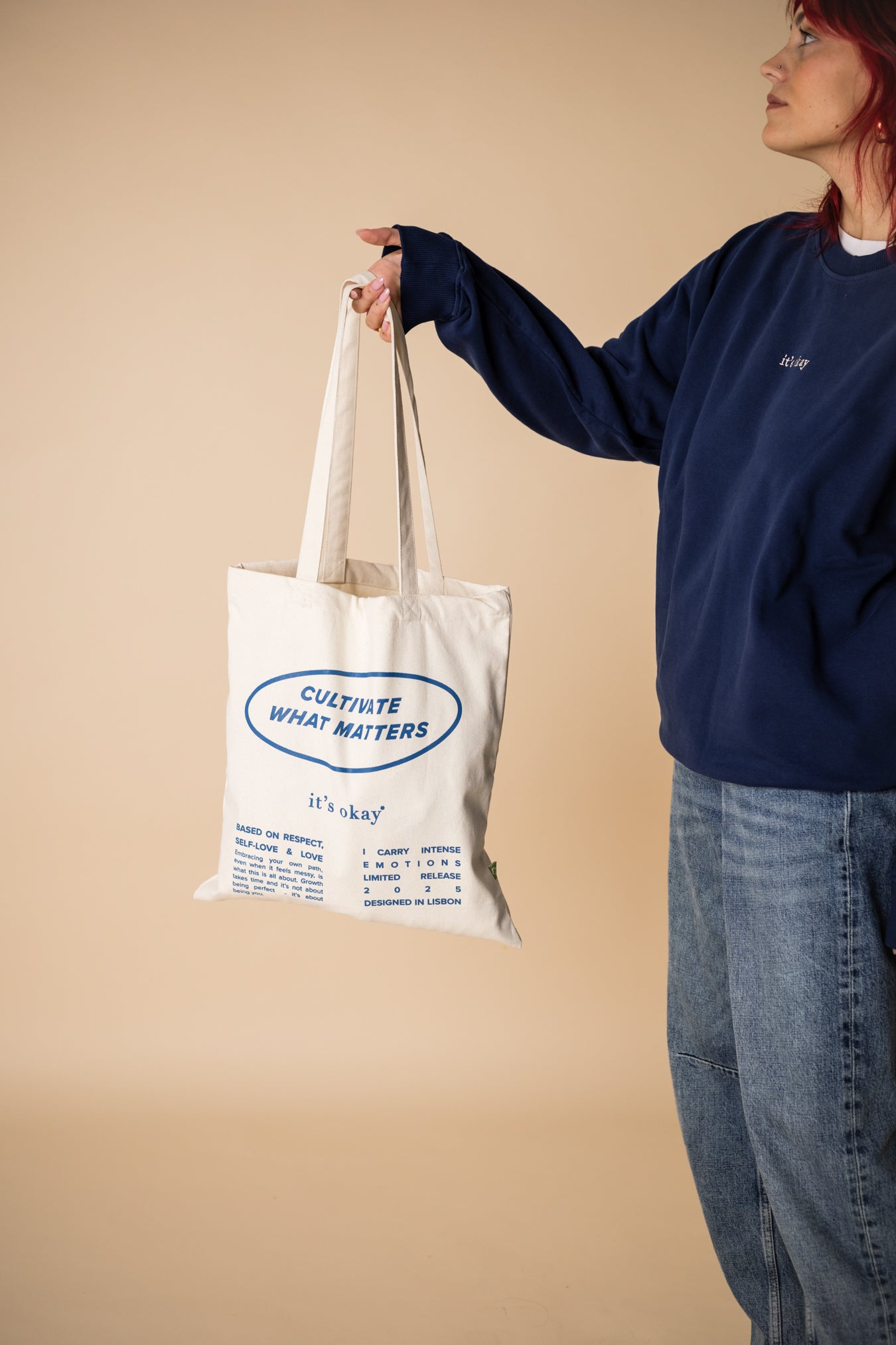 organic tote bag cultivate what matters, screenprinting, white and blue. Girl witrh crew blue pick up the tote bag.