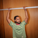 Man in a striped shirt standing inside an elevator with wooden walls. arms up