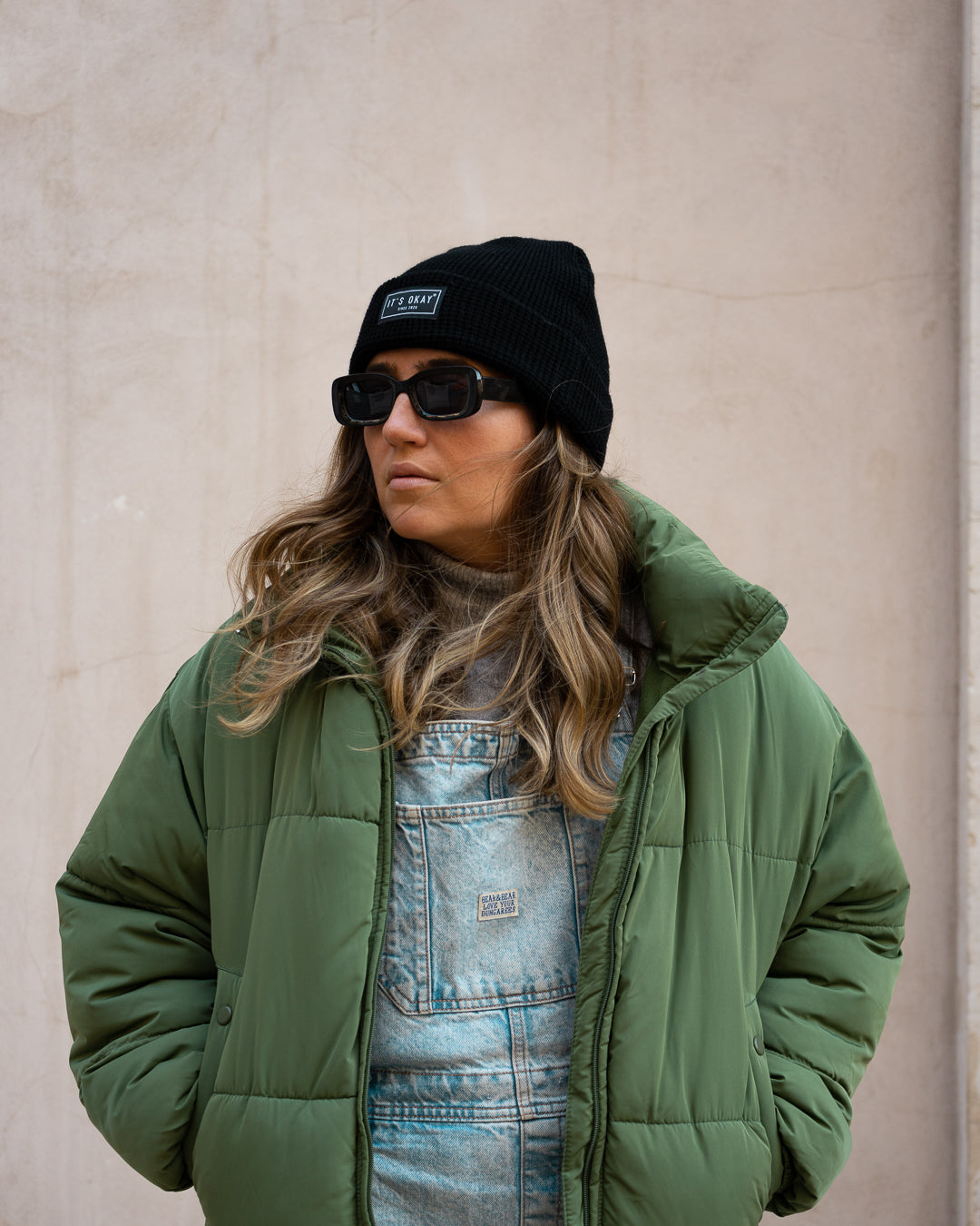Black Beanie from It's okay | made in Portugal with love | feel cozy and warm with this knitted beanie. Pt gorro de inverno it's okay em preto. Image: woman looking left with sunglasses wearing black waffle beanie