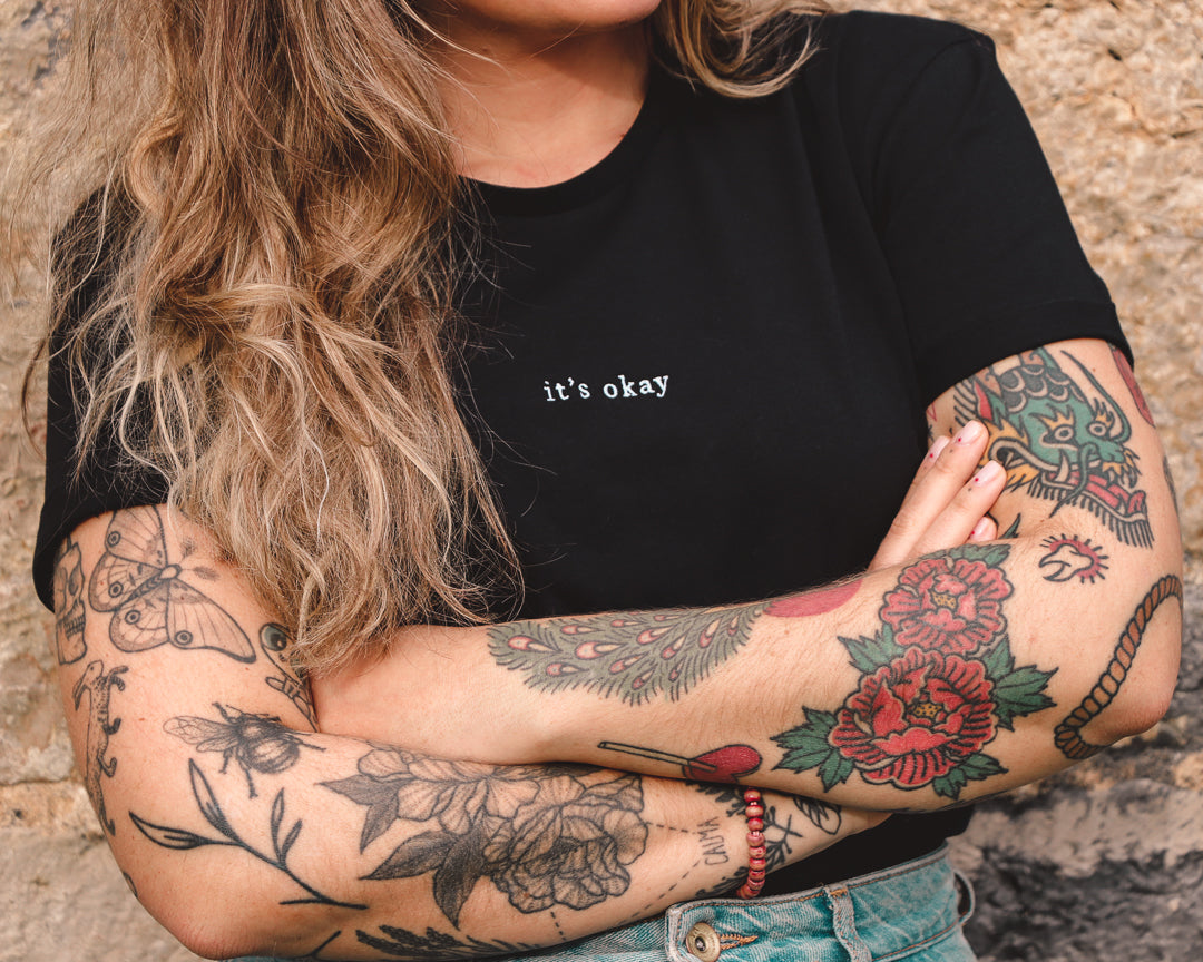 Organic t-shirt essential Black made in North of Portugal with love. Exclusive design made only for it's okay. T-shirt em algodão orgânico feito em portugal com amor | GOTS approved. Image: girl with arm tattoos wearing the organic essential tee