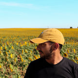 Sunflower cap, yellow cap made with 100% cotton, embroidered. it's okay to be exactly who you are. From Portugal with love. Boné de pala amarelo de algodão bordado em Portugal. Photography: Men with beard in a sunflower field wearing sunflower cap