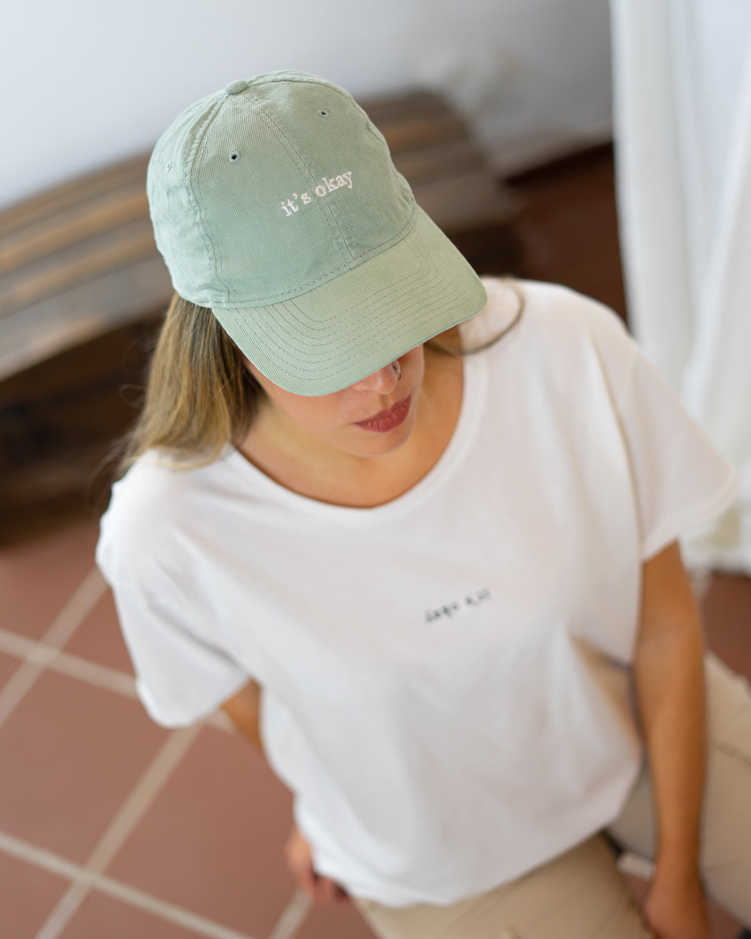 Wave cap | cotton needlecord corduroy in sage. Embroidered in Portugal. One size fits most | Wear it with pride. It's okay to be exactly who you are. Pt: Boné algodão de pala em bombazine de cor salvia, tamanha ajustável. Image: Wave cap on women wearing word search organic t-shirts from it's okay